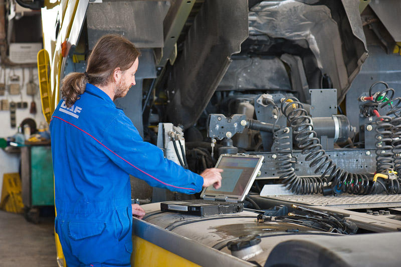 In der Werkstatt. LKW mit hochgeklapptem Führerhaus. Mechatronische Analyse mit Laptop